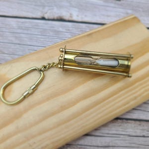 Discover the elegance of time with our Handmade Brass Sand Timer Keychain. Crafted with skillful artistry, this miniature hourglass captures the essence of both functionality and aesthetic appeal.