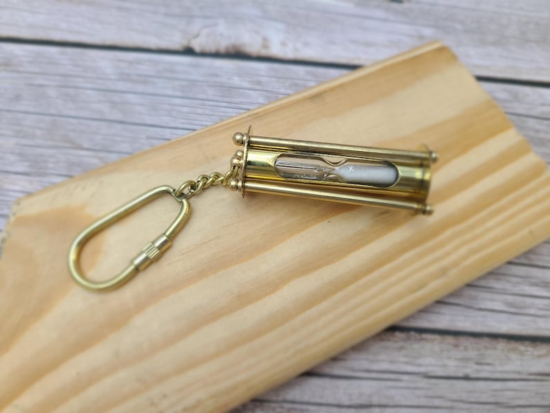 Discover the elegance of time with our Handmade Brass Sand Timer Keychain. Crafted with skillful artistry, this miniature hourglass captures the essence of both functionality and aesthetic appeal.