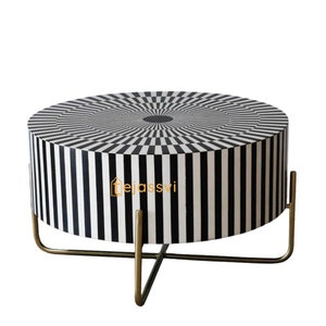 Op de afbeelding: Een ronde bijzettafel met een opvallend zwart-wit geometrisch patroon. De tafel heeft een cilindrisch lichaam met verticale strepen en een bovenkant met een radiaal dambordpatroon. Hij wordt ondersteund door een goudkleurige metalen basis.