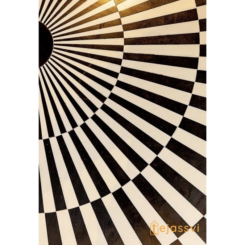 Op de afbeelding: Close-up van een zwart-wit patroon. Het ontwerp heeft een radiaal patroon met afwisselende zwarte en witte strepen, waardoor een geometrisch en optisch illusie-effect ontstaat. Het patroon doet denken aan een zonnestraal of een doel.