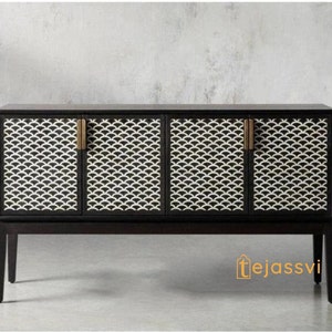 Op de afbeelding: Een zwarte kast met vier deuren en een wit en zwart waaiervormig patroon op de voorkant. De kast heeft messing handgrepen en staat op vier slanke poten. De kast is een meubelstuk.