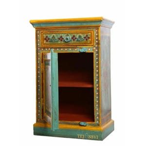 Può includere: Un piccolo mobile in legno dipinto a mano con un cassetto e una porta. Il mobile è dipinto in tonalità di verde acqua, giallo e arancione, con accenti floreali. La porta è aperta, rivelando un ripiano all'interno. Il testo "TEJ SSVI" è in basso.
