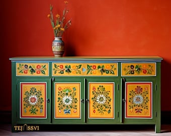 May include: A green wooden cabinet with four doors and three drawers, decorated with vibrant floral patterns. The cabinet features a yellow and blue top with floral designs. A vase of flowers sits atop the cabinet against a red wall.