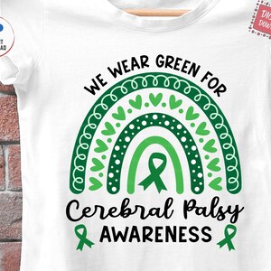 May include: Green and white design with a rainbow and the text "We Wear Green For Cerebral Palsy Awareness". A green ribbon is in the center of the rainbow.