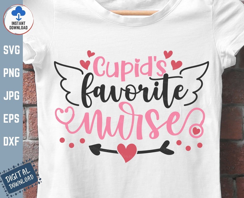 以下が含まれることがあります： ピンクと黒の文字で「Cupid's favorite nurse」と書かれた白いTシャツ。ピンクのハートと羽根が付いています。