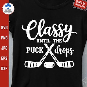 May include: White text on a black t-shirt that reads "Classy Until The Puck Drops".  Two hockey sticks are crossed in the center of the text with a heart in the middle.