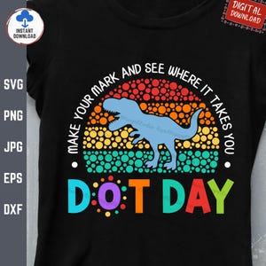 May include: A black t-shirt with a colorful retro-style design featuring a dinosaur and the text "Make your mark and see where it takes you. Dot Day."