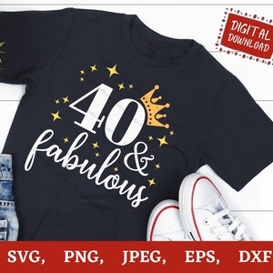 Puede incluir: Una camiseta azul oscuro con el texto "40 & fabulous" en blanco con una corona dorada y estrellas. La camiseta est&aacute; sobre una superficie de madera blanca.