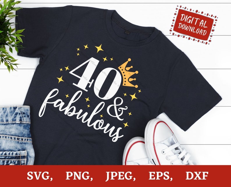 Puede incluir: Una camiseta azul oscuro con el texto "40 & fabulous" en blanco con una corona dorada y estrellas. La camiseta est&aacute; sobre una superficie de madera blanca.