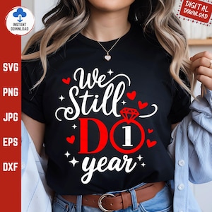 May include: Black t-shirt with the text "We Still Do 1 Year" in white and red. The design includes a diamond ring, hearts, and stars. The shirt is a digital download.