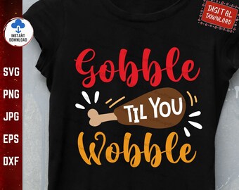 Może przedstawiać: Czarny T-shirt z napisem "Gobble Til You Wobble" w kolorze czerwonym i pomarańczowym. W środku napisu znajduje się kreskówkowa nóżka indyka.