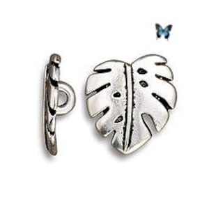 May include: A silver-toned metal toggle clasp set, featuring a leaf-shaped toggle and a bar. The leaf design has detailed veining and a central hole pattern. The clasp is designed for jewelry making and crafting.