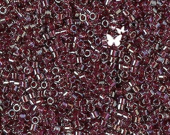 May include: A close-up image of a large quantity of small, dark purple glass beads. The beads are round and have a slightly iridescent finish.
