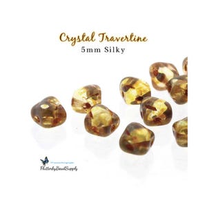 May include: Crystal Travertine 5mm Silky beads. These translucent beads have a mix of brown and yellow tones. The beads are irregularly shaped and appear to be made of a natural stone material. The image also includes the FlutterbyBeadSupply logo.