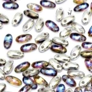 May include: A collection of small, oval-shaped beads with a metallic silver finish and iridescent highlights in shades of blue, purple, and gold. Each bead features a single central hole, creating a scattered pattern across the white background.