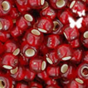 May include: A large quantity of small, round, red beads with white centers. The beads are made of glass and have a glossy finish.