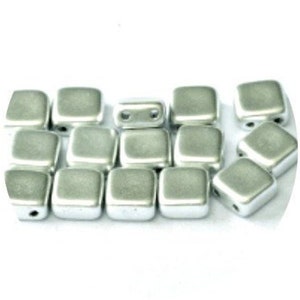 May include: A group of silver square beads with two holes each. The beads are arranged in a loose pile.
