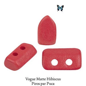 May include: Three red beads with a matte finish, including one pointed arch-shaped bead and two rectangular beads with two holes each. The text below reads Vogue Matte Hibiscus Piros par Puca, accompanied by a small blue and black butterfly icon.