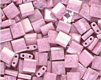 May include: A collection of rectangular, light pink glass beads with a marbled texture. Each bead features two parallel holes drilled through the centre. The surface of the beads has a glossy finish, and a small white butterfly icon is visible.