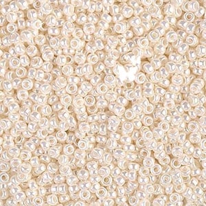 May include: A close-up shot of a pile of small, round, off-white beads. The beads have a pearlescent sheen, reflecting light. These beads are ideal for jewelry making and crafting projects.