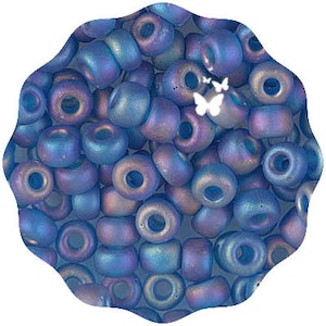May include: A large pile of iridescent blue glass beads. The beads are small and round with a hole in the center. They have a subtle shimmer and a slightly metallic finish.