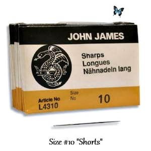 May include: A package of John James Sharps Longues sewing needles, size 10, with a black and white illustration of a snake on the front. The package is yellow and black with the text "Sharps Longues Nähnadein lang" and "Size No 10".