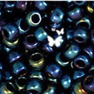 May include: A close-up of a large quantity of small, round, blue and purple beads. The beads have a metallic sheen and are arranged in a random pattern.