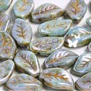 May include: A collection of light blue glass leaf-shaped beads with a subtle gold leaf design. The beads are approximately 1 inch long and have a slightly iridescent finish.