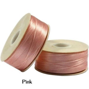 May include: Two spools of pink satin ribbon. The ribbon is wound around a cardboard core. The word "Pink" is printed in black at the bottom of the image. The ribbon has a slight sheen.
