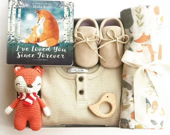 May include: A gift set containing a book titled I've Loved You Since Forever, a pair of beige soft-soled shoes, a beige waffle-knit long-sleeve shirt, a crocheted orange fox toy with a red and white scarf, a wooden bird-shaped teether, and a patterned swaddle.
