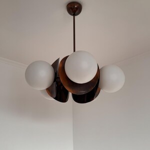 May include: A modern, mid-century style chandelier with five white globe-shaped light bulbs and a brown metal frame.