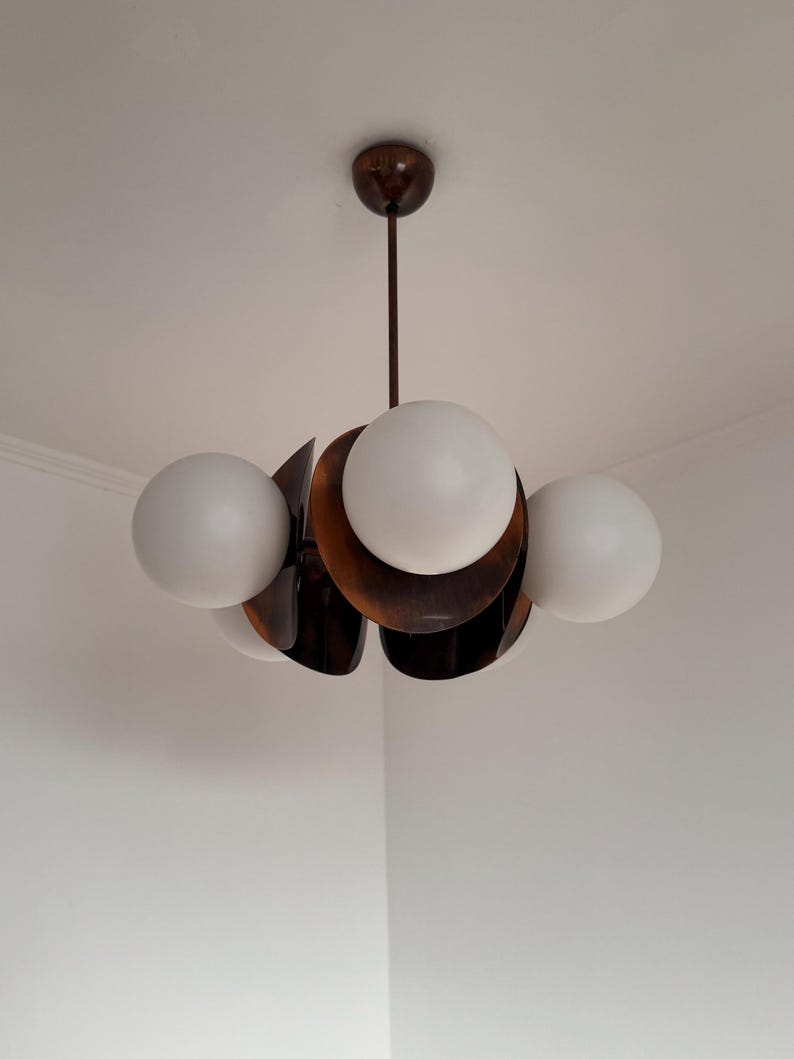 May include: A modern, mid-century style chandelier with five white globe-shaped light bulbs and a brown metal frame.