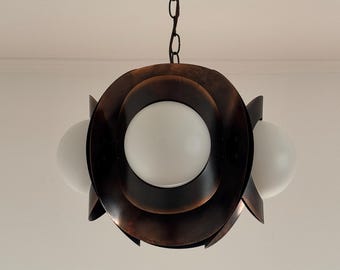 May include: A copper-toned pendant light fixture with three white glass globes. The fixture has a circular design with overlapping layers.