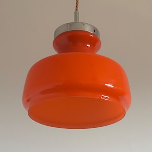 May include: Orange glass pendant light with a chrome finish. The light has a rounded, bulbous shape.