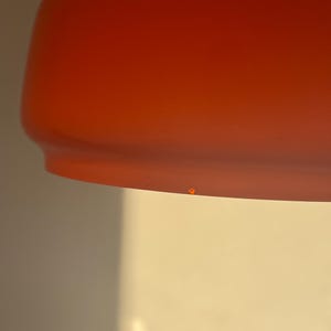 May include: A close-up of a bright orange lampshade with a slight imperfection on the bottom.