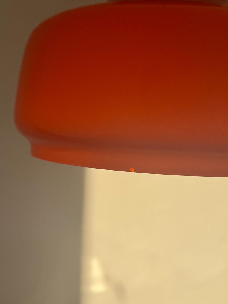 May include: A close-up of a bright orange lampshade with a slight imperfection on the bottom.