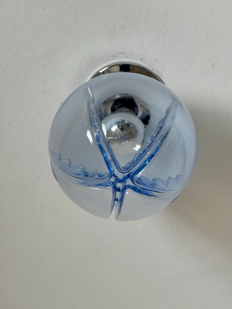 May include: A light blue glass globe light fitting with a chrome base. The globe has a starburst design in darker blue and a chrome bulb inside. The fitting is mounted on a white ceiling.