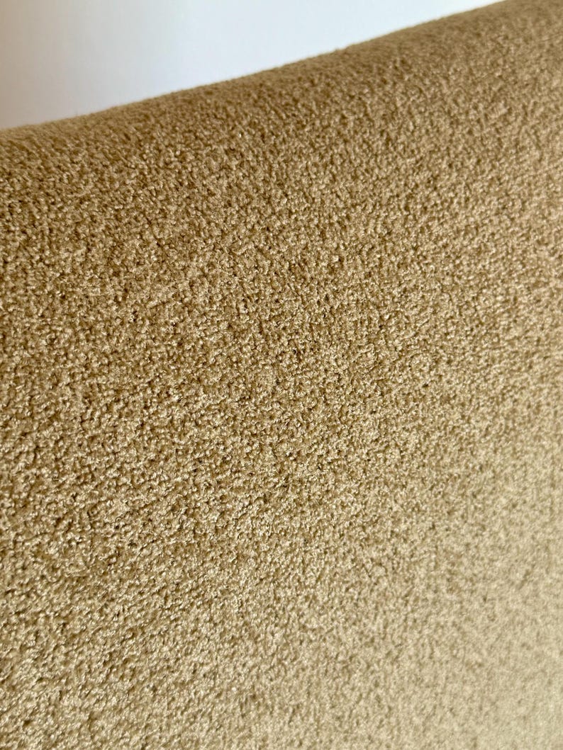 May include: Close-up of a light brown, textured fabric. The fabric has a soft, fuzzy appearance.