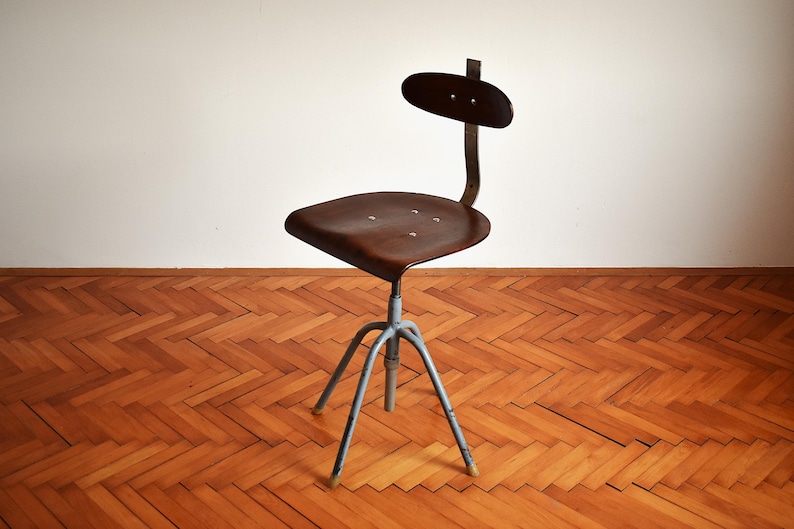 May include: A vintage industrial chair with a dark brown wooden seat and a metal backrest. The chair has a swivel base with three legs and is painted a light blue color.