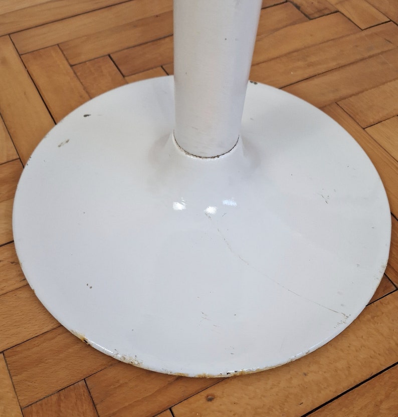 May include: White metal table base with a round, wide base and a tall, slender column.