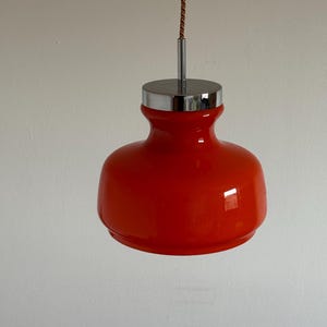 May include: A red glass pendant light with a chrome top and a brown cord.