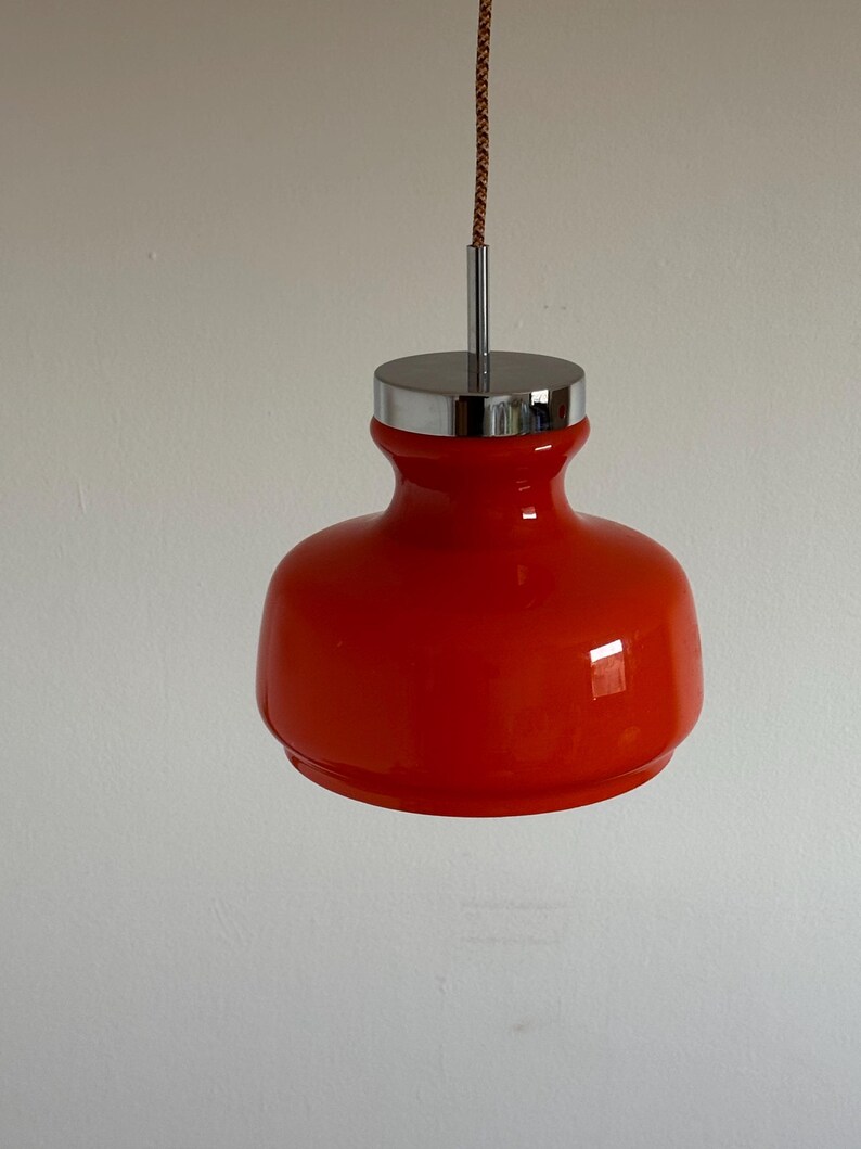 May include: A red glass pendant light with a chrome top and a brown cord.