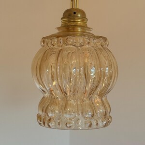 May include: A gold-toned pendant light with a clear, ribbed glass shade. The shade has a textured, bubble-like pattern.