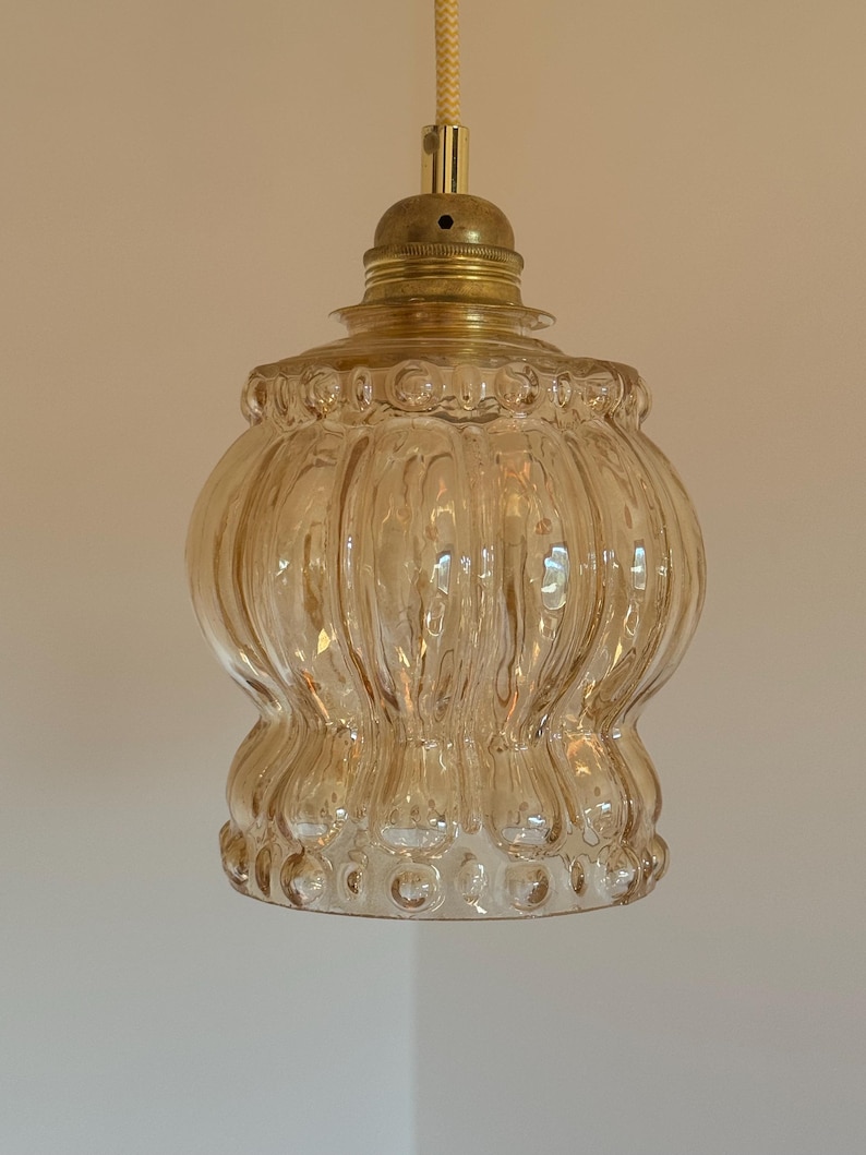 May include: A gold-toned pendant light with a clear, ribbed glass shade. The shade has a textured, bubble-like pattern.