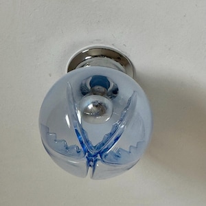 May include: A light blue glass globe light fitting with a chrome base. The globe has a spherical shape with a decorative blue design. The light bulb is visible inside the globe.