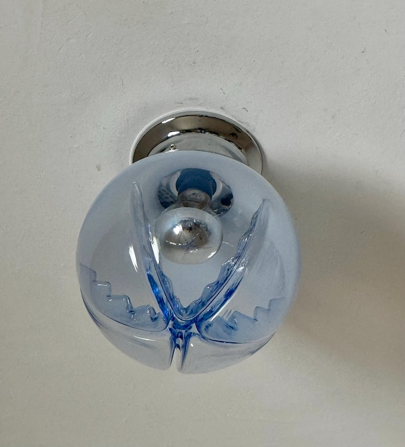 May include: A light blue glass globe light fitting with a chrome base. The globe has a spherical shape with a decorative blue design. The light bulb is visible inside the globe.