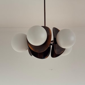 May include: A mid-century modern chandelier with five white glass globes and a brown metal frame.