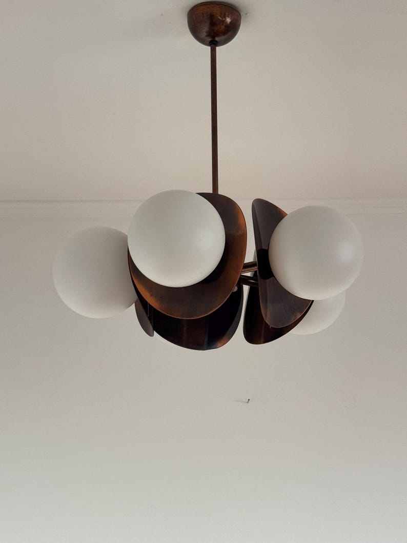 May include: A mid-century modern chandelier with five white glass globes and a brown metal frame.