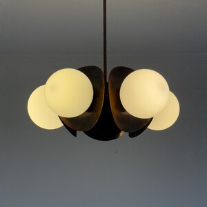 May include: A mid-century modern chandelier with five white glass globes and a brass finish.