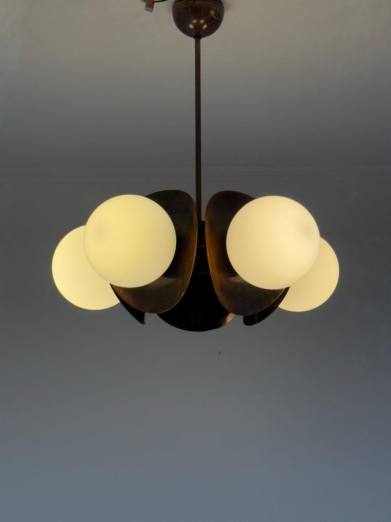 May include: A mid-century modern chandelier with five white glass globes and a brass finish.